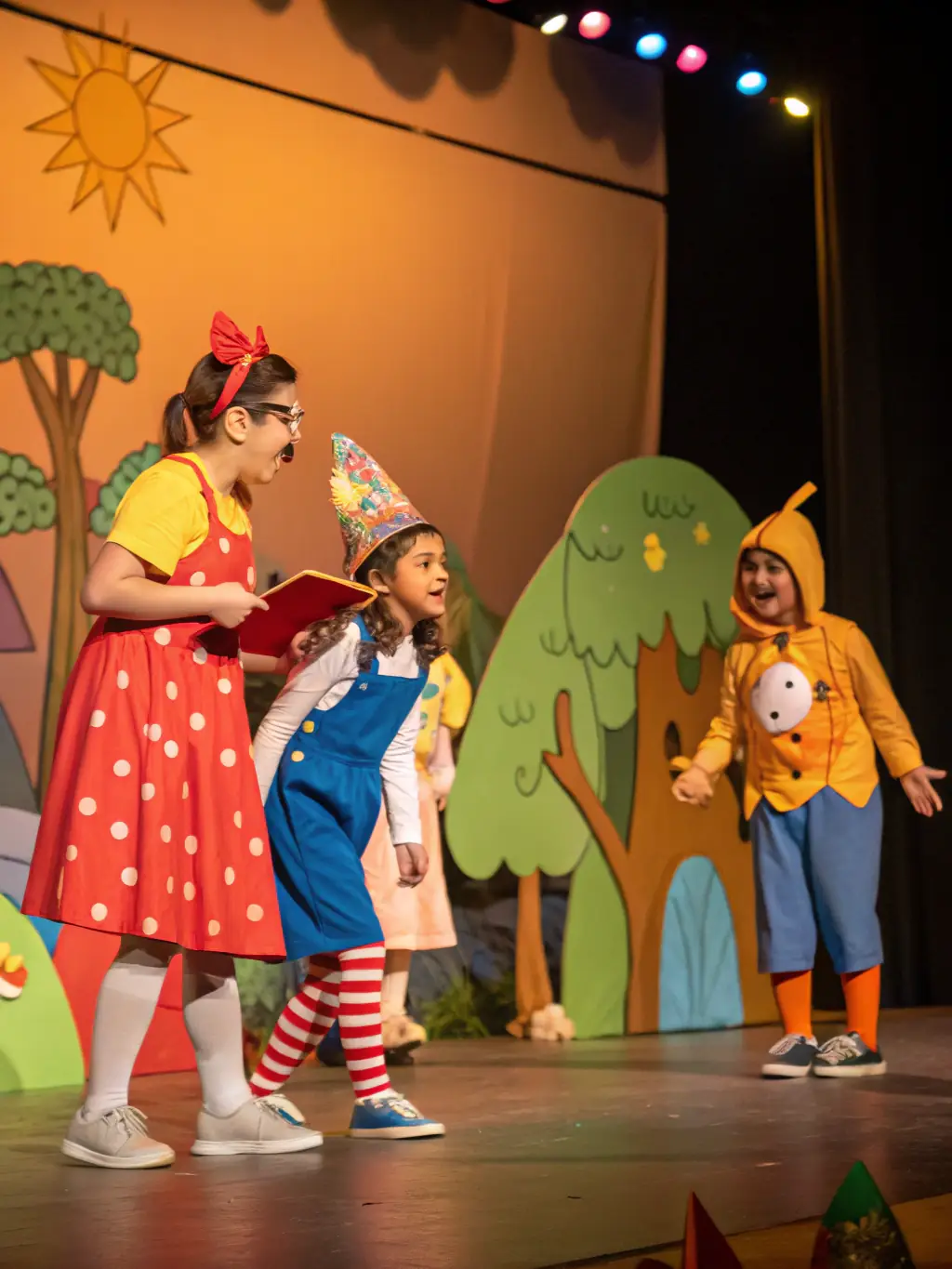 A group of students performing a play on stage with colorful costumes and props.
